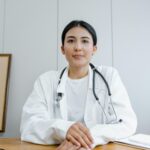 Nữ bác sĩ mặc áo blouse trắng đeo ống nghe đang ngồi tư vấn tại phòng khám.